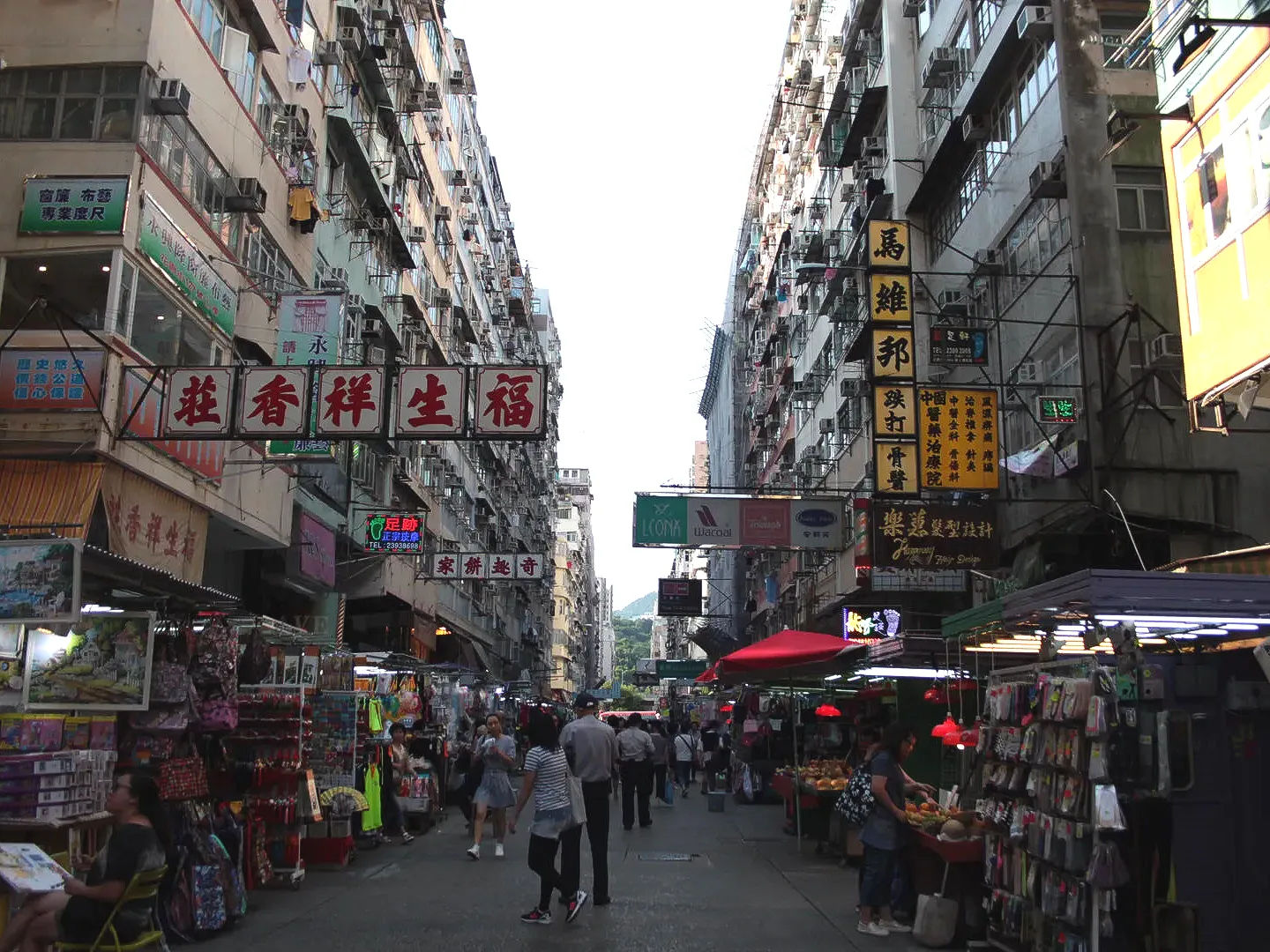 Widok zatłoczonej ulicy handlowej na Mong Kok z wiszącymi nad nią szyldami w Hongkongu