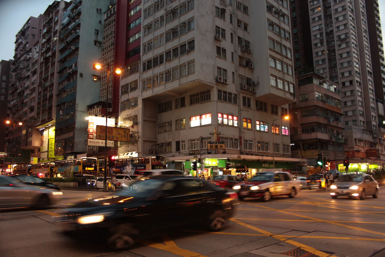 Nocny widok na ruchliwą ulicę w Kowloon, Hongkong, z samochodami i budynkami mieszkalnymi w tle
