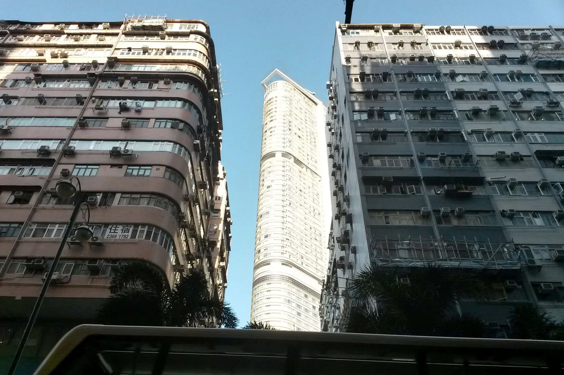 Nowoczesny wieżowiec między dwoma starszymi budynkami mieszkalnymi w dzielnicy Kowloon, Hongkong