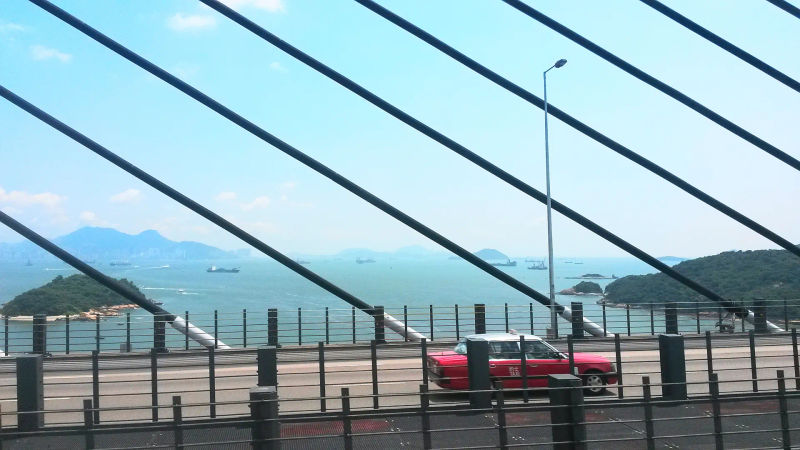 Widok na port morski z mostu w Hongkongu, z wieloma statkami na tle górskich wysp