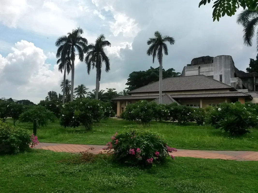 Nowoczesny budynek w tropikalnym ogrodzie z palmami i roślinami w tle.