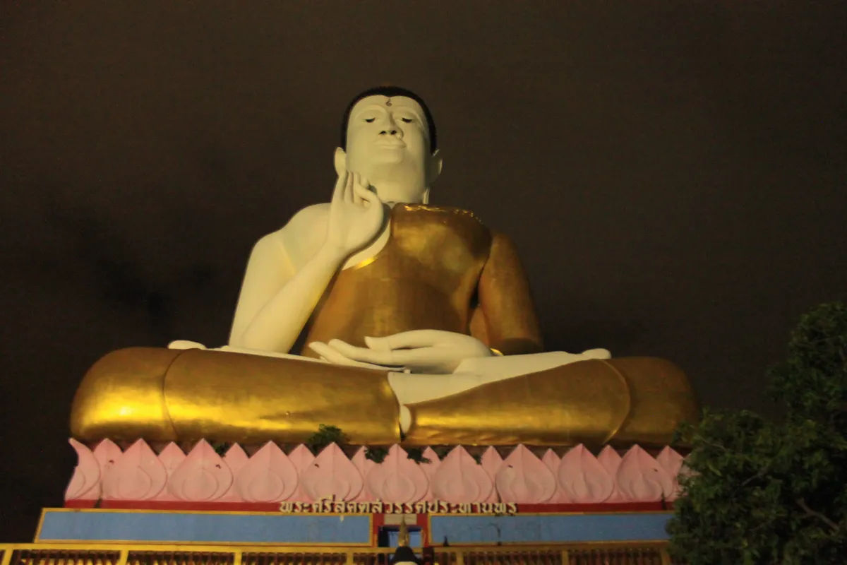 Posąg Buddy w Nakhon, Thailand, w tle oświetlone miasto.