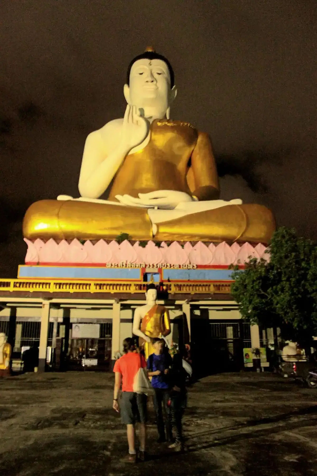 Posąg Buddy w Nakhon, Thailand, w tle oświetlone miasto.