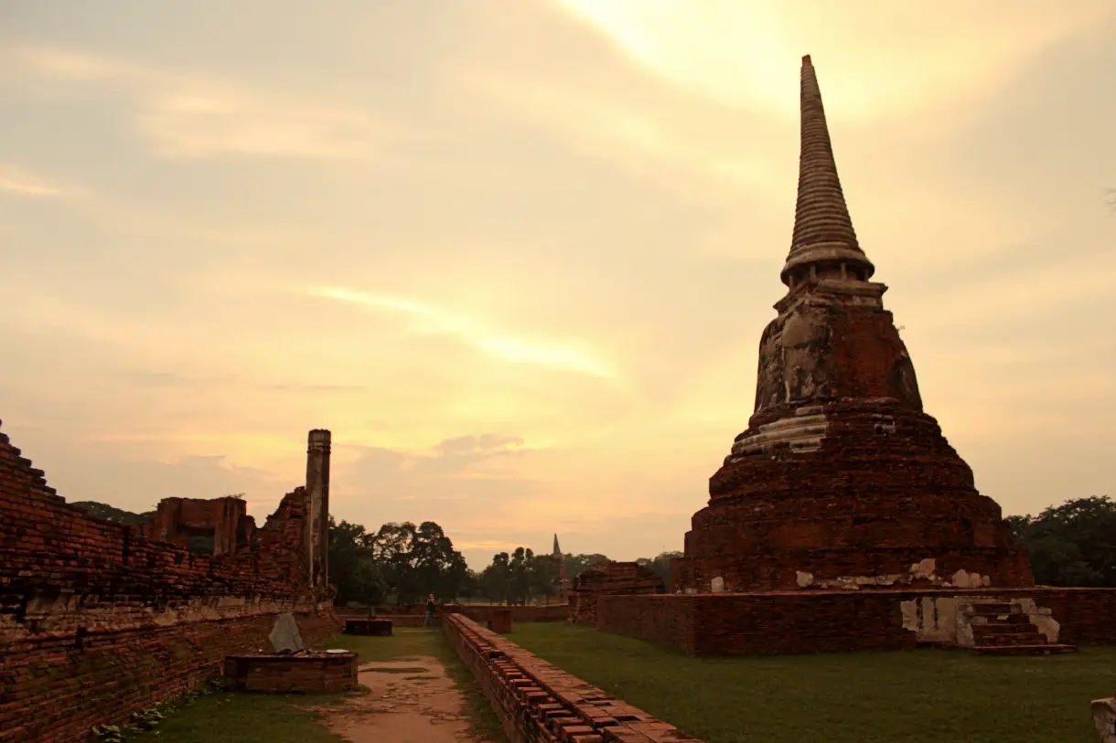 Widok zrujnowanej świątyni w Ayutthaya, z ceglaną konstrukcją w tle.