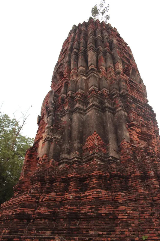 Zbliżenie na posąg Buddy w ruiny w Ayutthaya, otoczony ceglaną architekturą.