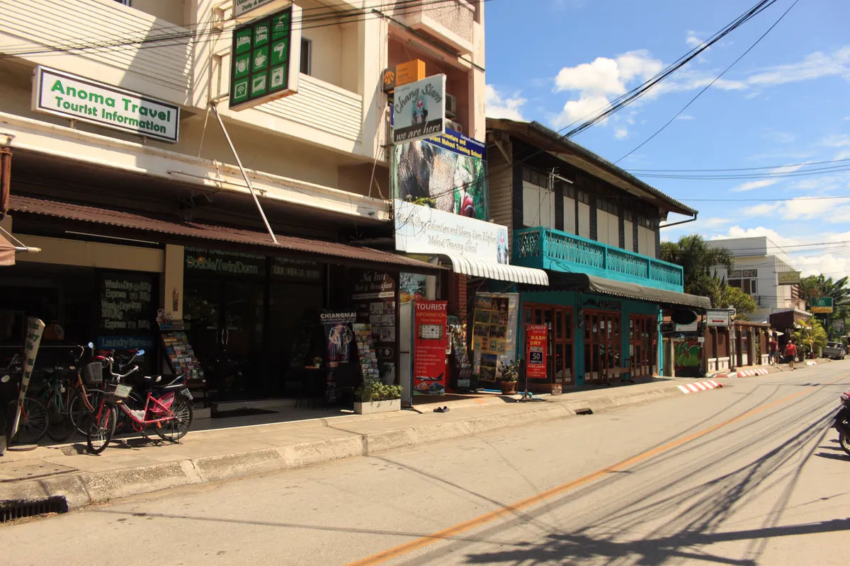 Tradycyjna ulica z wąską drogą w Chiang Mai, pełna tuk-tuków i lokalnych sklepów.
