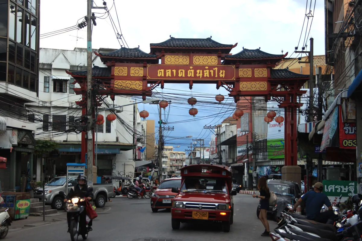 Tradycyjna ulica z wąską drogą w Chiang Mai, pełna tuk-tuków i lokalnych sklepów.