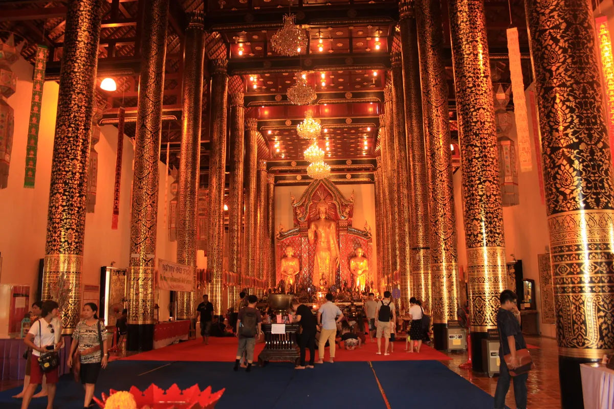 Wnętrze świątyni Wat Chedi Luang, wypełnione złotymi kolumnami i posągami Buddy.