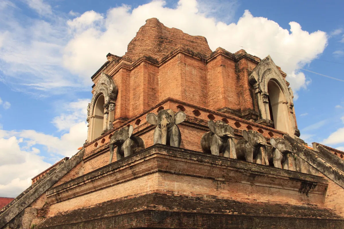 Zabytkowa ceglana stupa w Wat Chedi Luang w Chiang Mai, otoczona figurkami słoni.