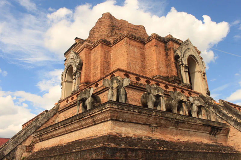 Zabytkowa ceglana stupa w Wat Chedi Luang w Chiang Mai, otoczona figurkami słoni.