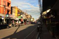 Tradycyjna ulica z wąską drogą w Chiang Mai, pełna tuk-tuków i lokalnych sklepów.