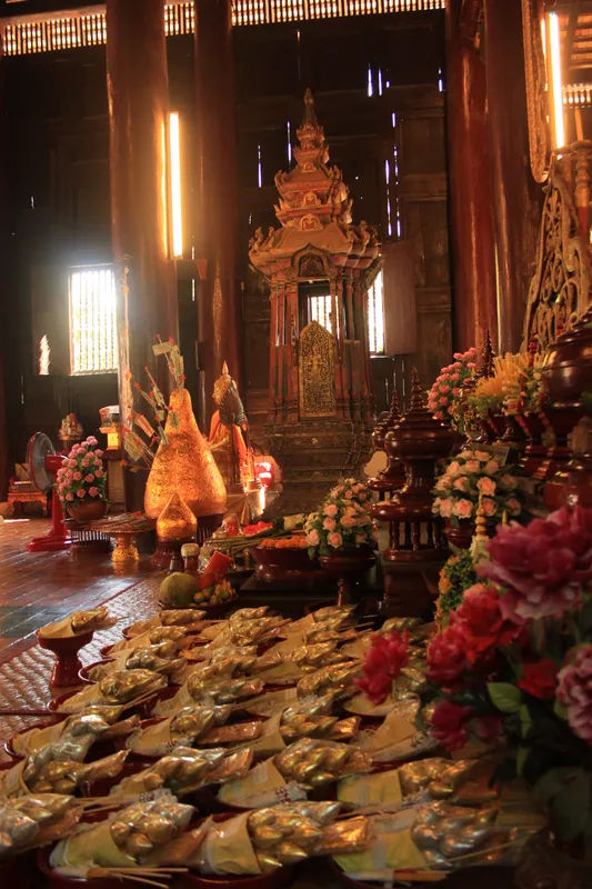 Zbliżenie na dekoracje w świątyni Wat Phan Tao w Chiang Mai z ofiarami i kwiatami.