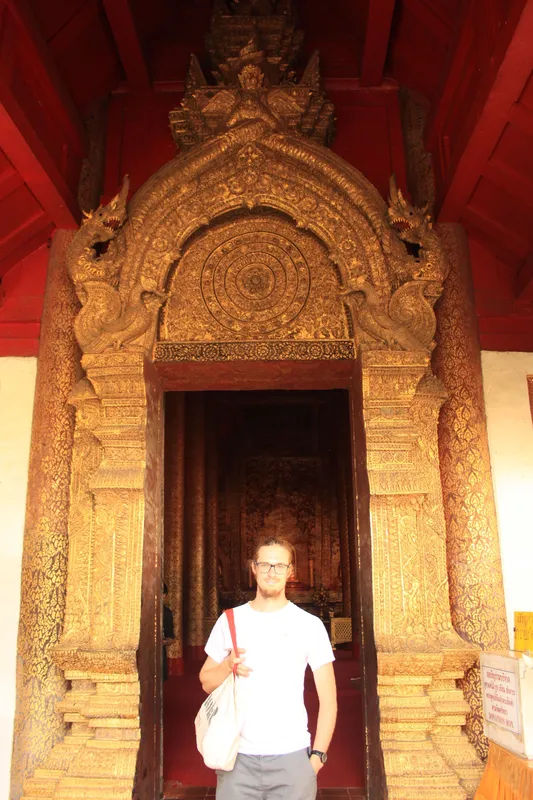 Zdobione złotem wejście do świątyni Wat Phra Singh, przedstawiające skomplikowane detale rzeźbiarskie.