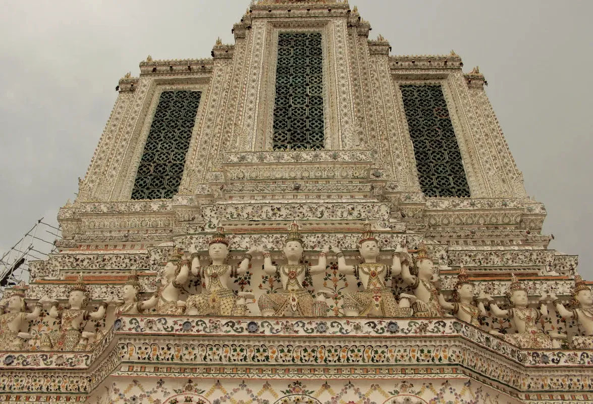 Zdobienia na wieży Wat Arun w Bangkoku, przedstawiające figury i kolorowe mozaiki.