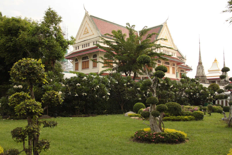 Widok na kompleks Wat Arun w Bangkoku, z misternie zdobioną architekturą i ogrodami.