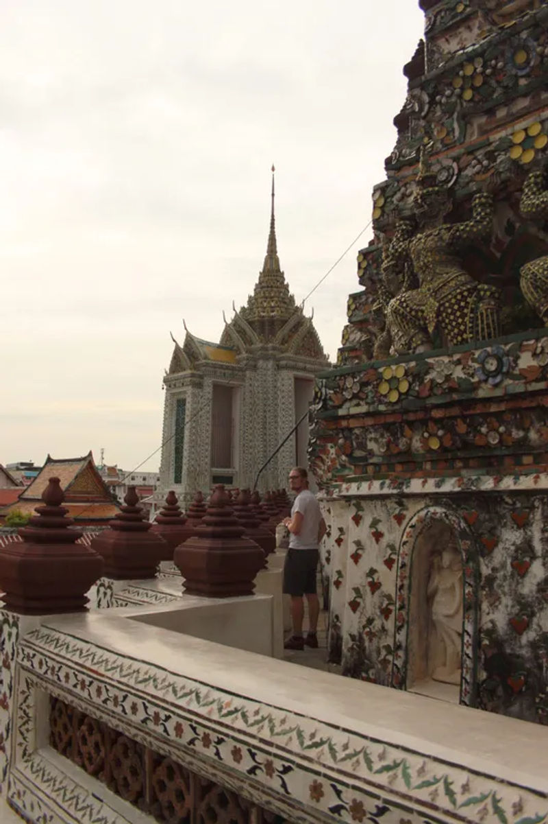 Stairs leading to the top of the Wat Arun pagoda in Bangkok with intricate tile details.