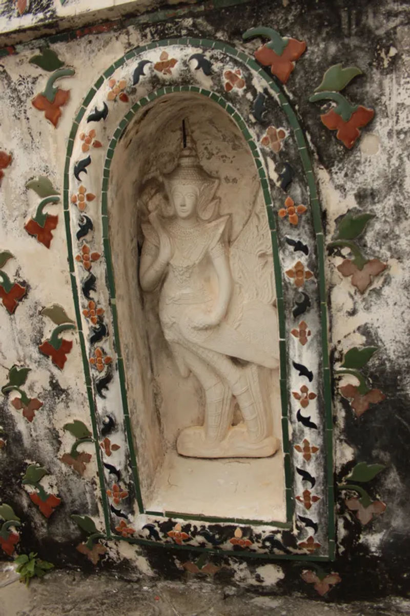 Zbliżenie na dekorację w Wat Arun, z postaciami i ceramicznymi detalami.