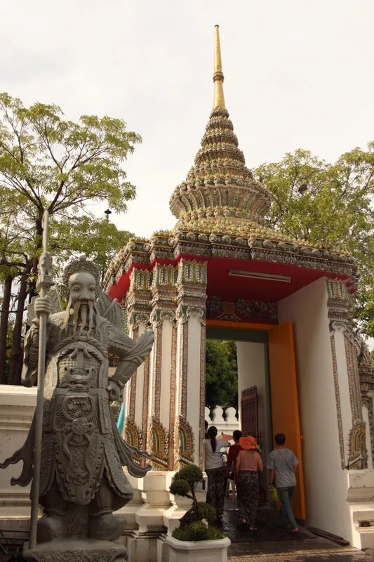 Posąg chińskiego strażnika w Wat Pho w Bangkoku, z misternymi detalami architektonicznymi.