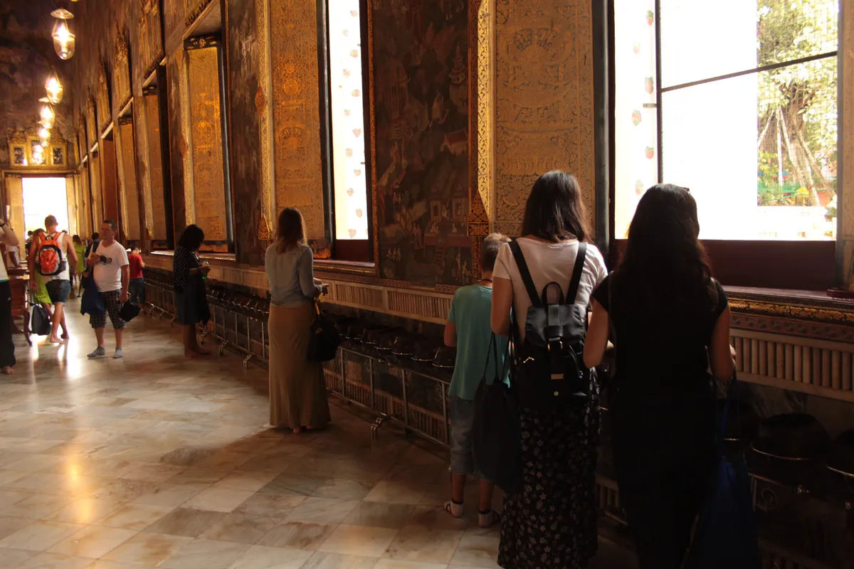 Posąg Buddy w Wat Pho, w tle złote detale dekoracyjne.
