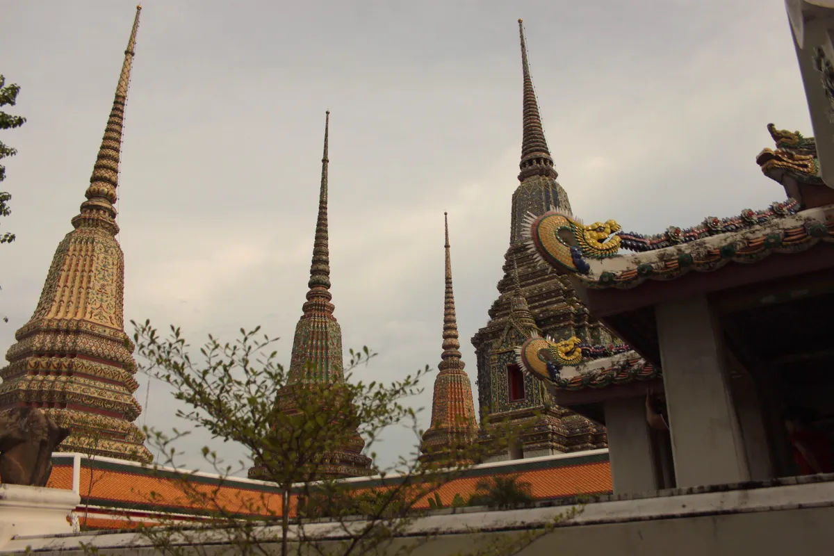 Stupy w Wat Pho z widokiem na tradycyjną tajską zabudowę świątynną.