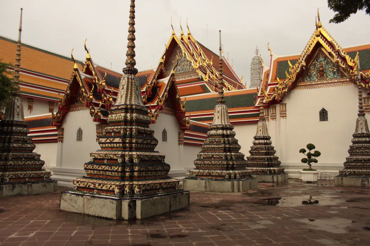Stupy w Wat Pho w Bangkoku w tle z tradycyjną tajską architekturą.