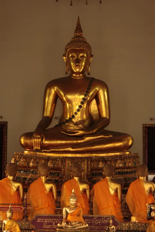 Złocisty posąg Buddy w Wat Pho w Bangkoku, siedzący na ołtarzu.