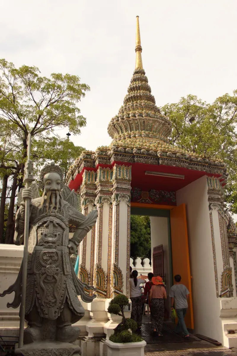 Posąg chińskiego strażnika w Wat Pho w Bangkoku, z misternymi detalami architektonicznymi.