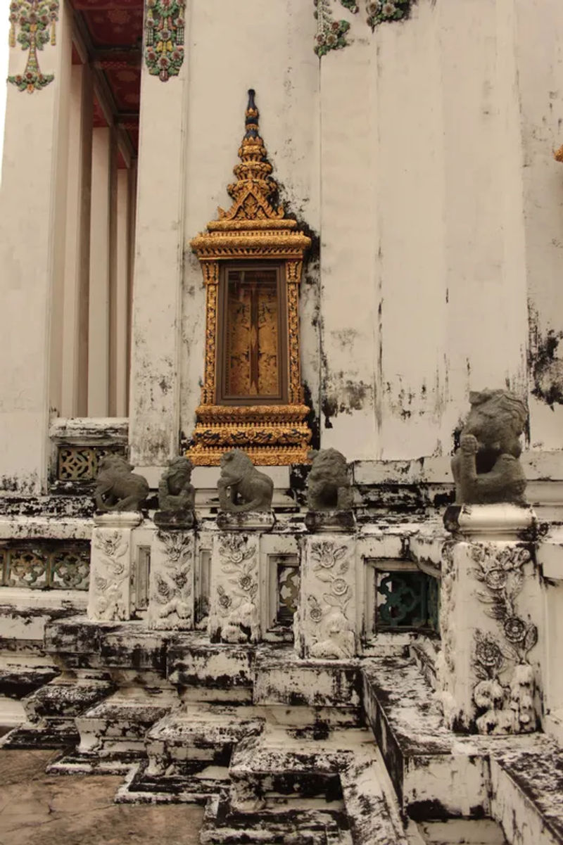 Zbliżenie na kamienne posągi w Wat Pho, Bangkoku, przedstawiające mistyczne postacie.