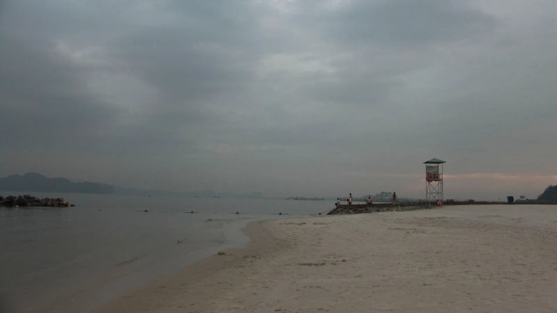 Opustoszała plaża z wieżą obserwacyjną na tle pochmurnego nieba, Wietnam.