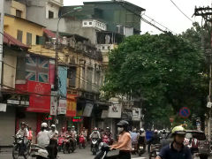 Ruch uliczny w Starej Dzielnicy Hanoi, z motocyklistami i budynkami o kolonialnej architekturze w tle