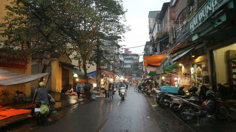 Nocny targ na ruchliwej ulicy w Hanoi z motocyklistami i pieszymi,