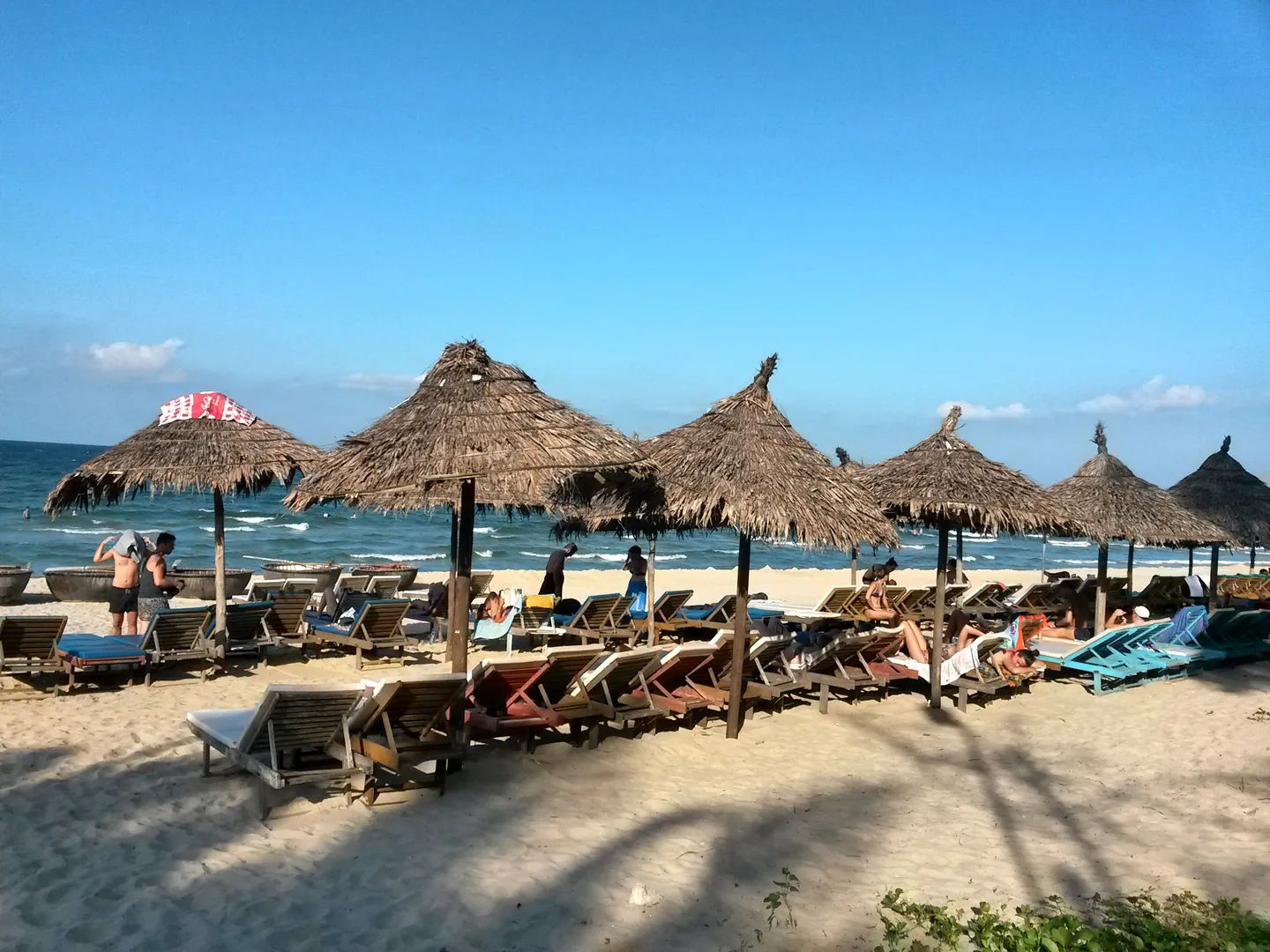 Plaża z leżakami i słomianymi parasolami, turyści wypoczywający nad morzem, Wietnam.