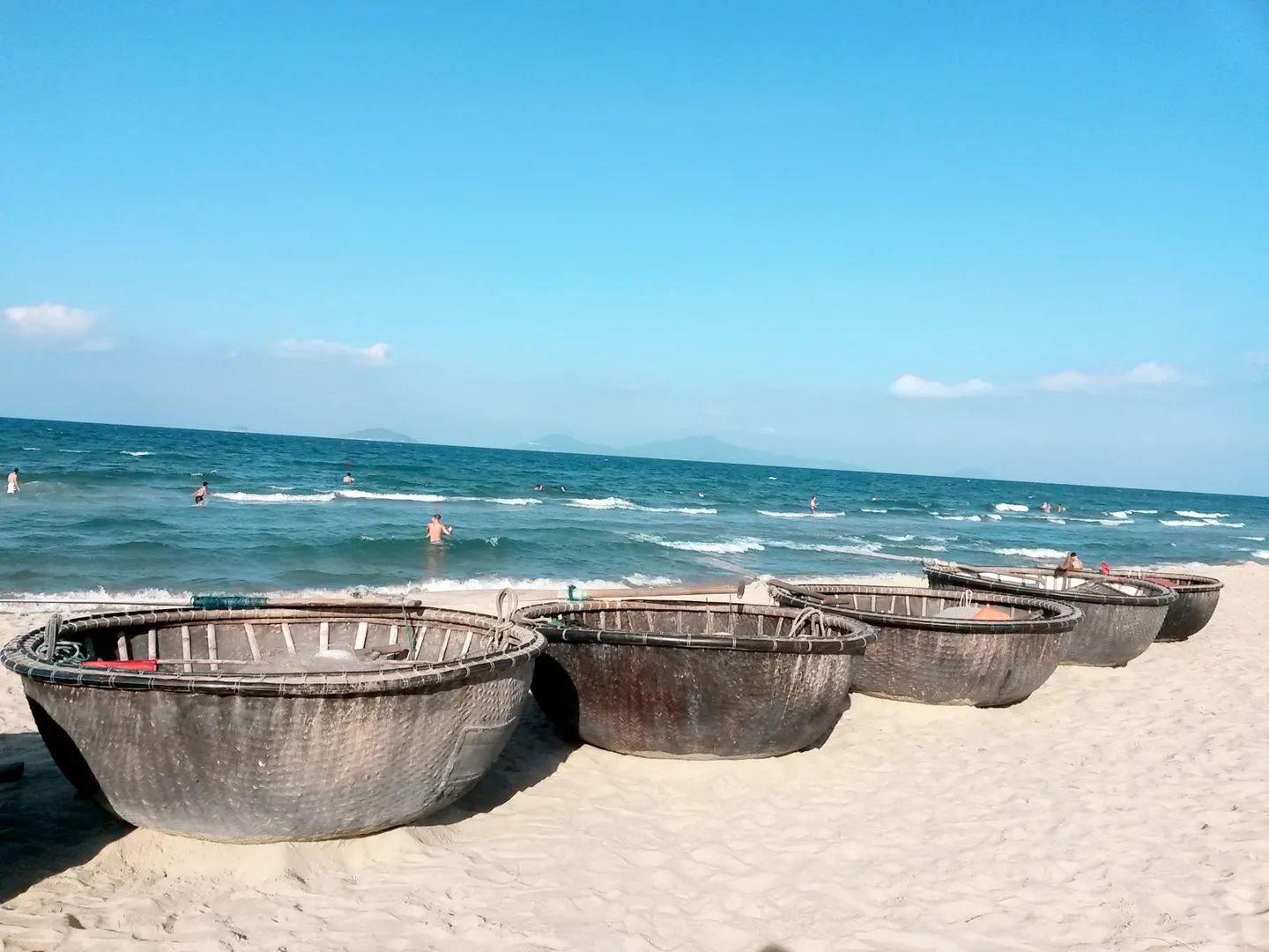 Tradycyjne okrągłe łodzie na piaszczystej plaży z widokiem na morze, Wietnam.