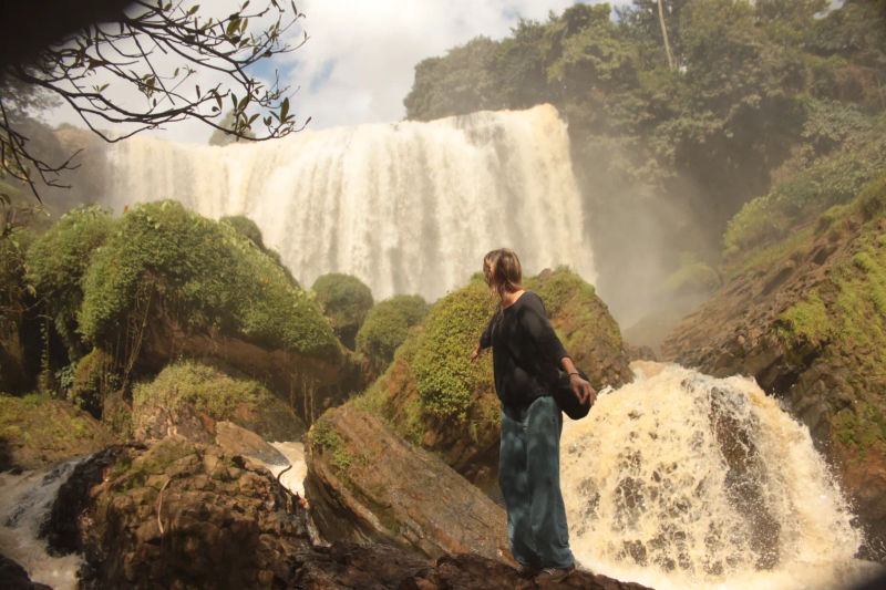 Kobieta stojąca bokiem do wodospadu Sloni, Dalat