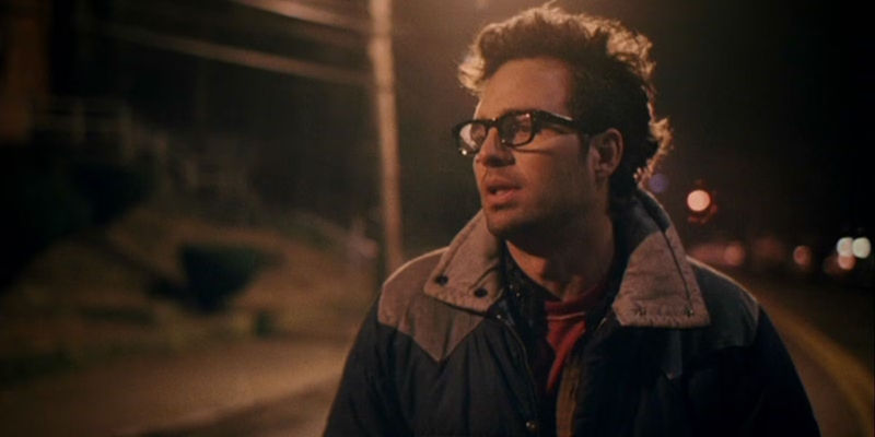 Clementine holds a coffee cup and looks sad while Joel lies down and sleeps in bed in bed Eternal Sunshine of the Spotless Mind