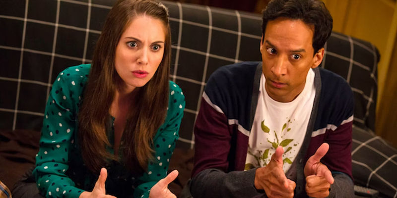 Alison Brie and Danny Pudi as Annie and Abed sitting on couch in Community pointing