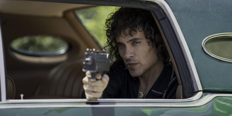 Rivi from Griselda pointing a gun