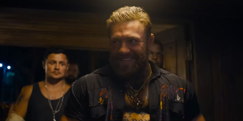 Conor McGregor in Road House entering through the door with his squad and smiling