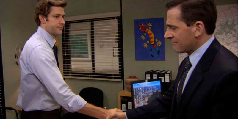 John Krasinski as Jim Halpert shaking hands with Steve Carell as Michael Scott in The Office