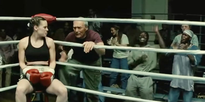 An image of a fan cheering while Maggie and Frank talk in the boxing ring in Million Dollar Baby