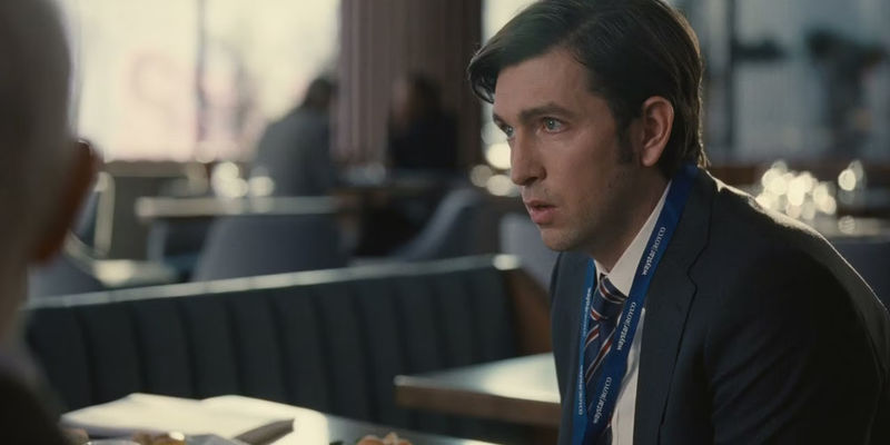 Greg sits in a restaurant in Succession