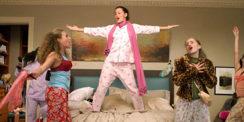 Jennifer Garner dancing on a bed in 13 Going on 30 with other teenagers dancing and singing around her