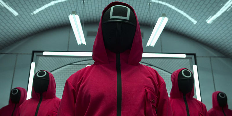 Masked figures in red jumpsuits in Squid Game