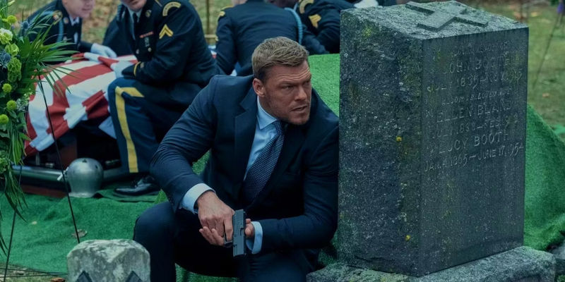 Reacher takes cover behind a gravestone in Reacher season 2