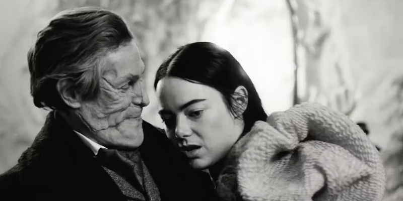 Deformed Willem Dafoe looking at surprised Emma Stone on his chest in Poor Things