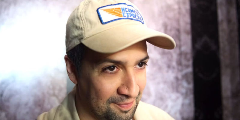 Hermes smiling in a Hermes Express cap in Percy Jackson and the Olympians episode 3