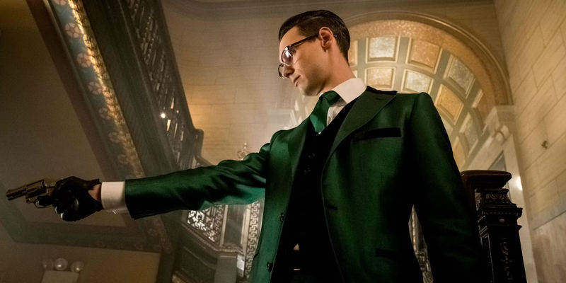 Riddler holding out a gun and wearing a green suit in Gotham
