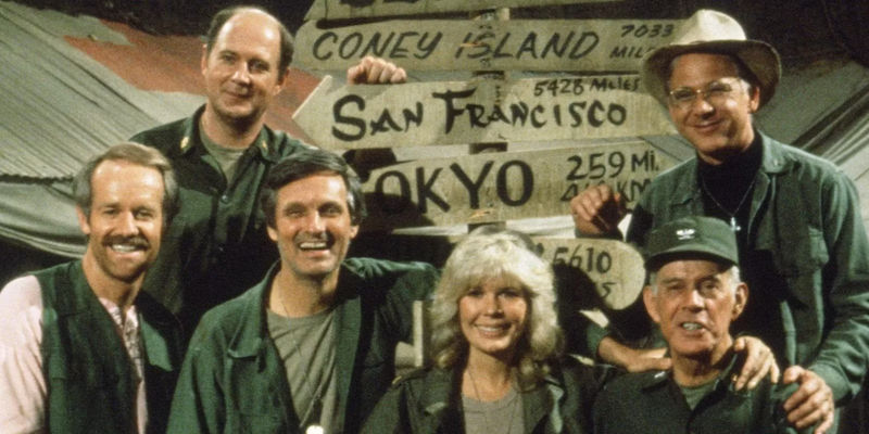 The cast of MASH with city signposts in the background