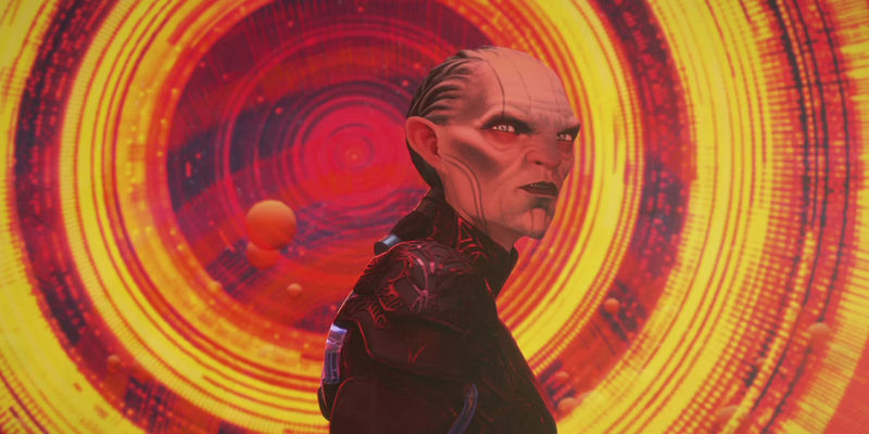 The Diviner, a pale humanoid alien in dark armor, with a backdrop of yellow concentric circles, in Star Trek: Prodigy.