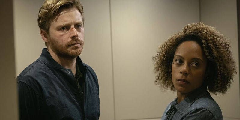 Jack Lowden as River and Rosalind Eleazer as Louisa in front of grey wall in Slow Horses